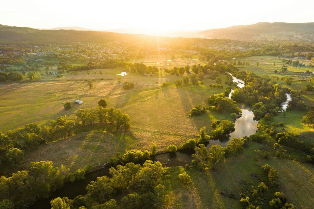 Aerial view of Tumut at golden hour with the river winding through green farmland.
