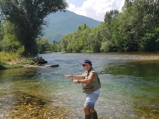 Fly fishing in a clear river near Tumut with mountains in the background.